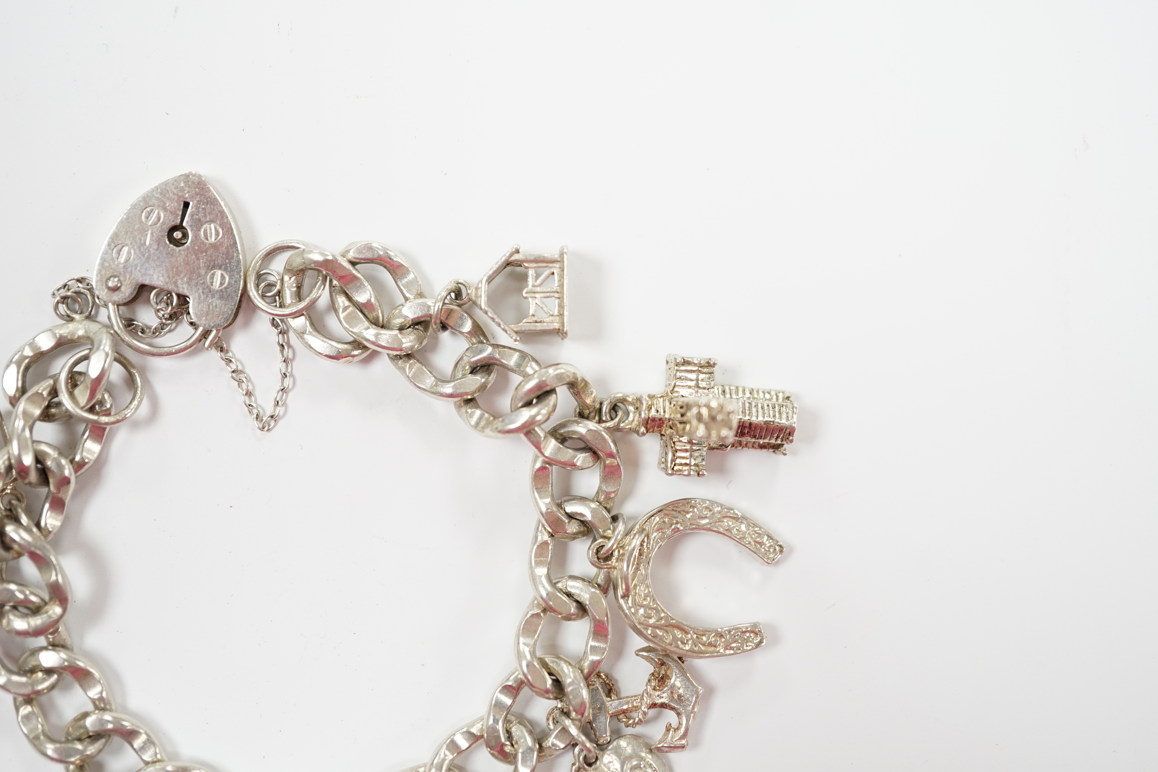 A modern silver charm bracelet, hung with nine assorted charms.
